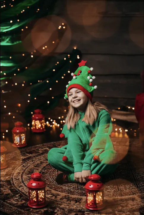 A laughing girl in an elf costume sitting among Christmas lanterns