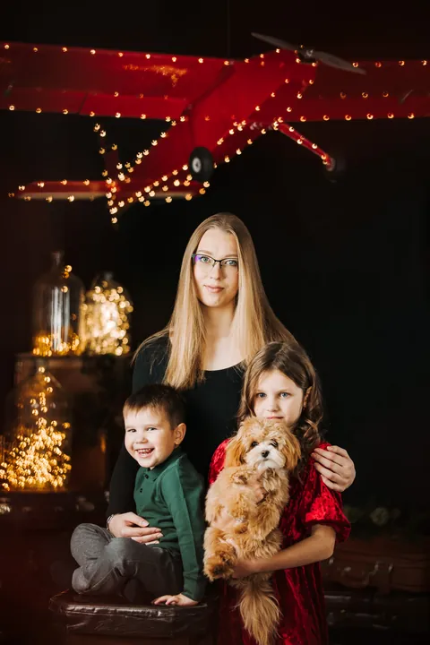 A mother, son and daughter with a dog under a red plane in Merle's Christmas studio