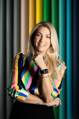 Photographer Merle Värv in a colourful striped blouse in front of her studio's colourful backdrops