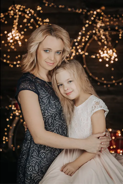 A mother and daughter hugging in front of golden lights